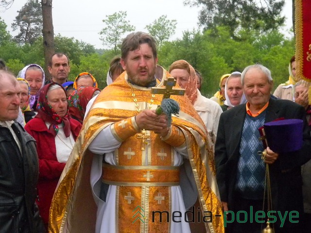 Священник читает молитву, окропляя храм и прихожан святой водой