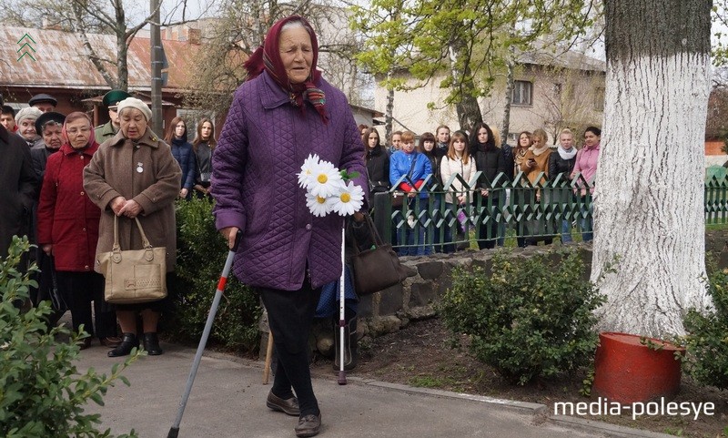 Бывшие узники несут цветы к памятному знаку