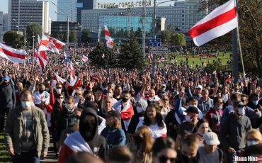 Демонстранты в Минске проходят под зданием с надписью «Минск — город-герой». Фото Надежды Бужан