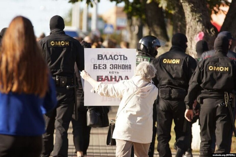 Пожилая женщина стыдит ОМОН в Гомеле плакатом «Власть без закона есть банда». Фото Svaboda.org