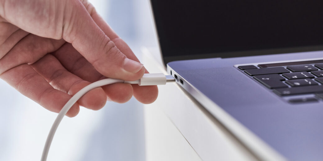 Laptop charger in hands close up. Discharged low battery at comp